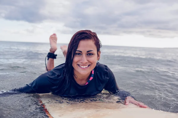 Portret van een vrouw over surfplank in water zwemmen — Stockfoto