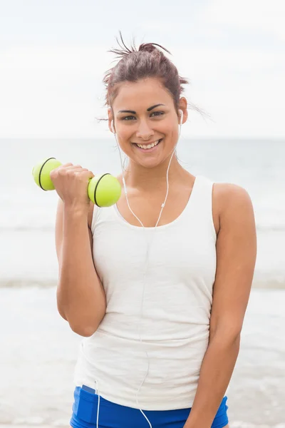 Cheerful smiling woman lifting dumbbells standing on beach — Stock Photo, Image