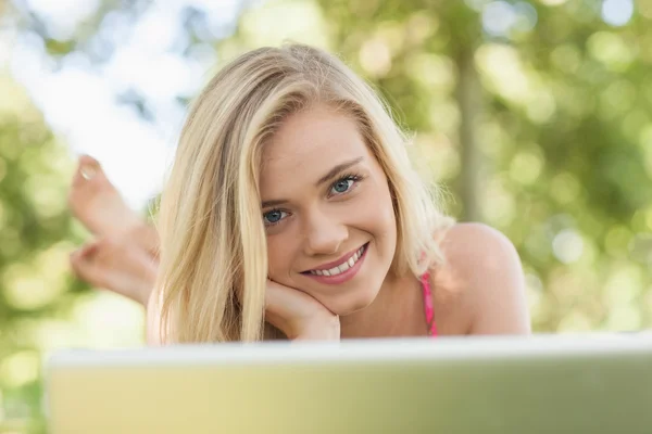 Fröhliche junge Frau vor ihrem Heft liegend — Stockfoto