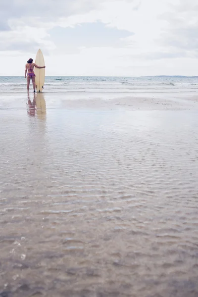 Spokojna kobieta w bikini z deską surfingową na plaży — Zdjęcie stockowe