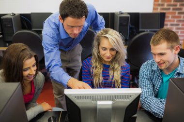 Teacher showing something on screen to students in computer room clipart