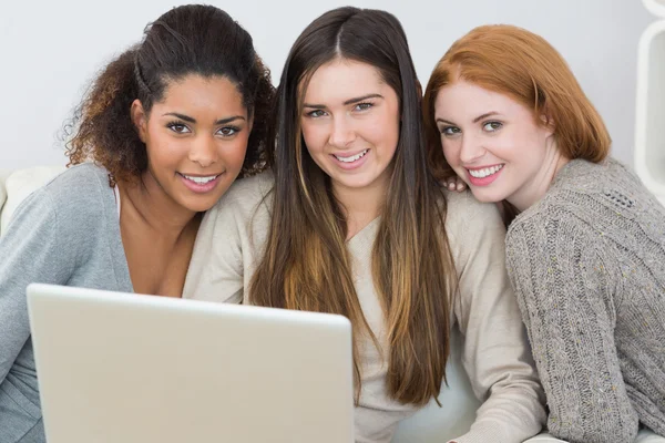 Retrato de amigos felizes usando laptop juntos no sofá — Fotografia de Stock