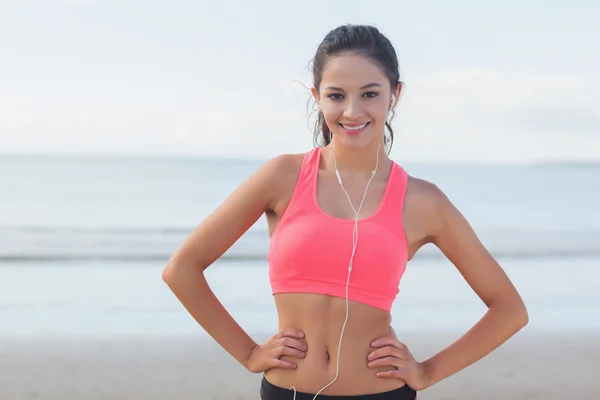Lächelnde gesunde Frau mit Kopfhörern am Strand — Stockfoto