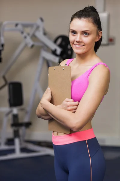 Χαμογελαστά γυναικεία εκπαιδευτής με πρόχειρο στο γυμναστήριο — Φωτογραφία Αρχείου