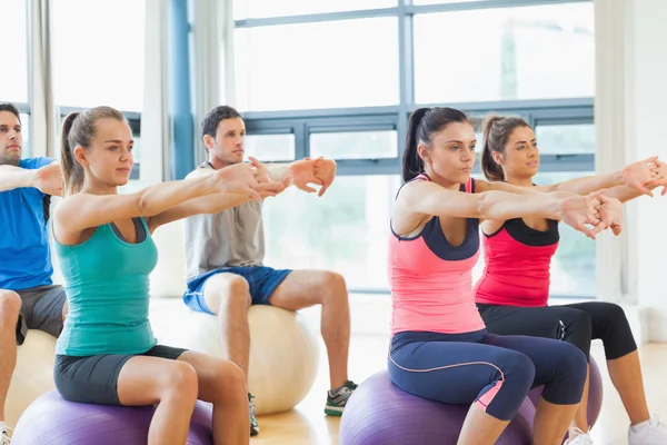 Sporty people stretching out hands on exercise balls at gym — Stock Photo, Image