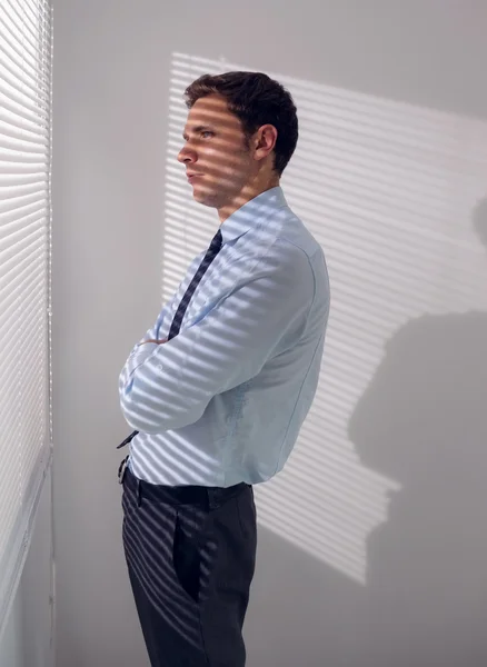 Businessman peeking through blinds in office — Stock Photo, Image