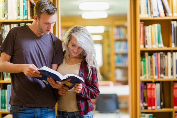 Студенты, стоящие у книжной полки в библиотеке — стоковое фото