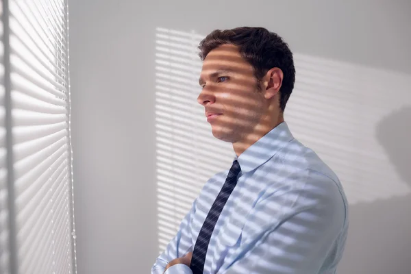 Бизнесмен подглядывает через жалюзи в офисе — стоковое фото