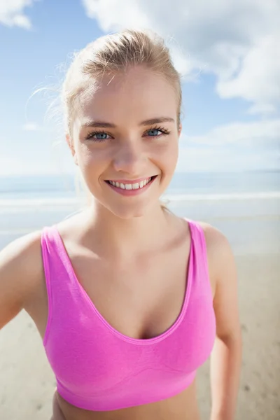 Sonriente mujer sana en rosa sujetador deportivo en la playa — Foto de Stock