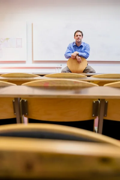 Elegante mannelijke leraar zitten in de collegezaal — Stockfoto