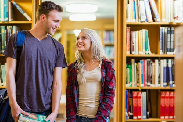 Students standing by bookshelf in the library — Stock Photo, Image