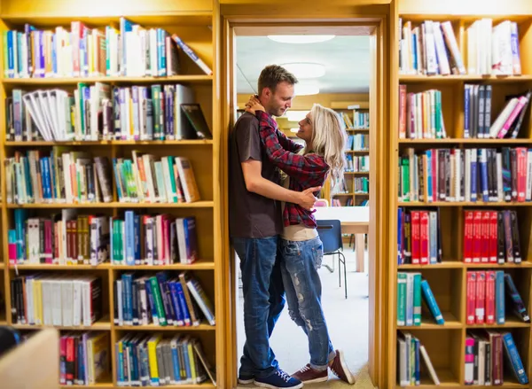 Studenten stehen in der Bibliothek am Bücherregal — Stockfoto