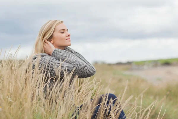 Sidovy av en söt eftertänksam kvinna som sitter på stranden — Stockfoto