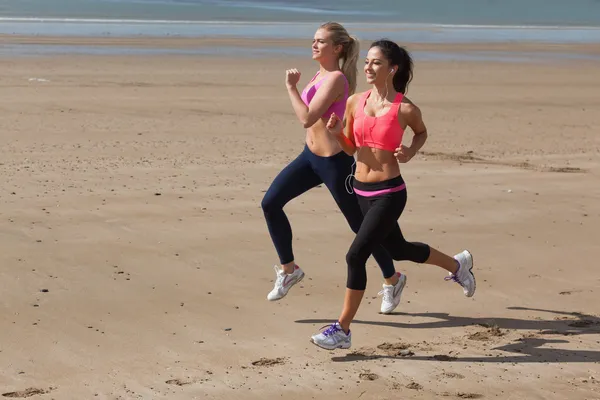 Lunghezza completa di donne sane che fanno jogging sulla spiaggia — Foto Stock