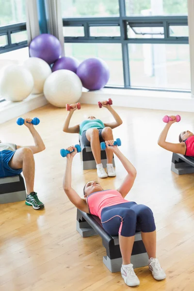 Istruttore con classe di fitness che esegue esercizi di step aerobica con manubri — Foto Stock