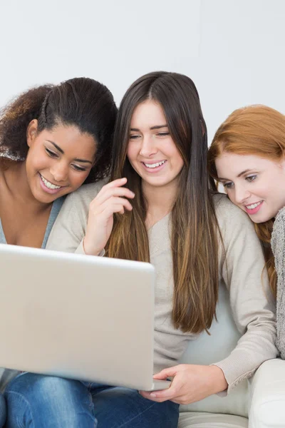 Alegre amigos femeninos usando el ordenador portátil juntos en el sofá —  Fotos de Stock