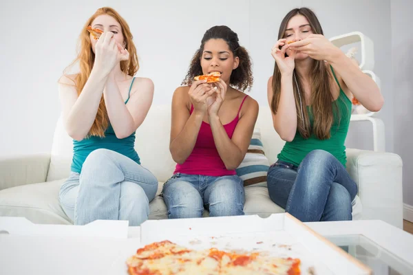 Happy young female friends eating pizza at home — Stock Photo, Image