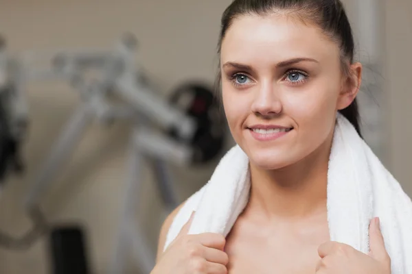 Leende ung kvinna med handduk runt halsen i gym — Stockfoto