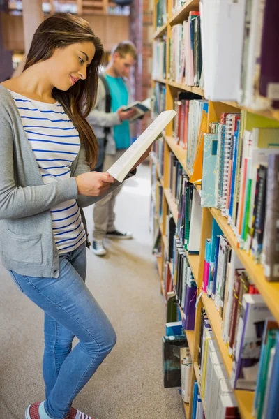 Twee studenten door boekenplank in de bibliotheek — Stockfoto