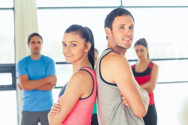 Fittes Paar mit Freunden im Hintergrund im Fitnessraum — Stockfoto