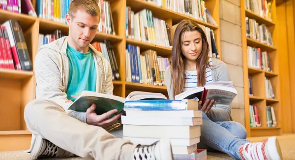 Studenti čtení knih na podlaze knihovny — Stock fotografie