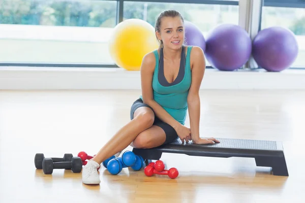 Mladá žena, sedící s činkami v fitness studio — Stock fotografie