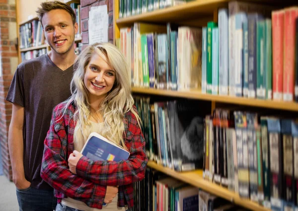 Студенты, стоящие у книжной полки в библиотеке — стоковое фото