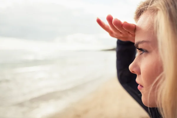 Vue latérale d'un beau blond blindage yeux à la plage — Photo