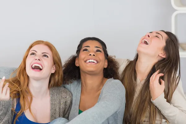 Vrolijke jonge vrouwelijke vrienden thuis lachen — Stockfoto