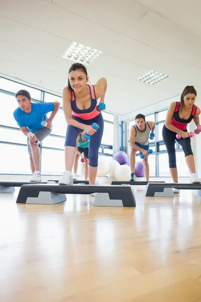 Istruttore con classe di fitness che esegue esercizi di step aerobica con manubri — Foto Stock