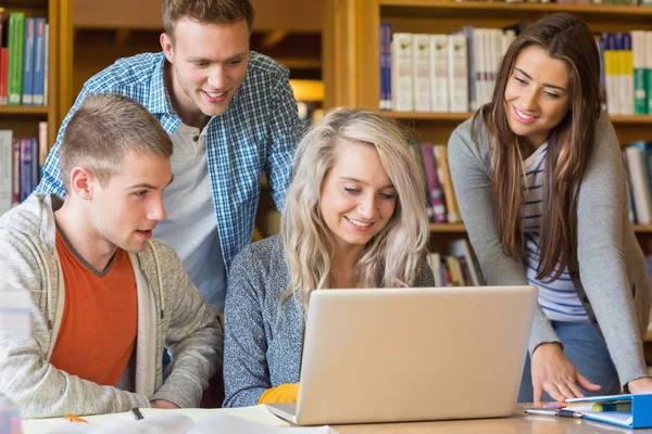 Estudiantes felices usando laptop en el escritorio en la biblioteca — Foto de Stock