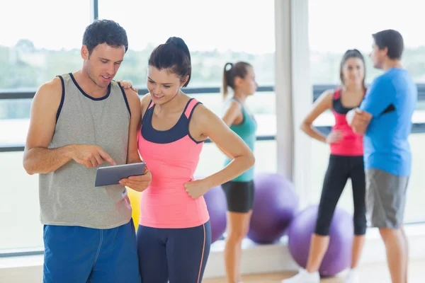 Fittes Paar schaut auf digitalen Tisch mit Freunden im Hintergrund — Stockfoto