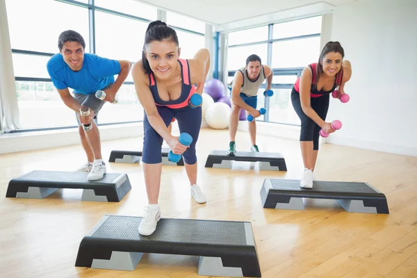 Instructor with fitness class performing step aerobics exercise with dumbbells — Stock Photo, Image