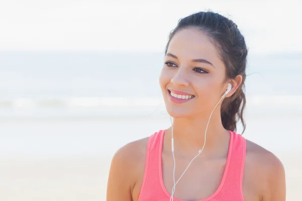 Lächelnde gesunde Frau mit Kopfhörern am Strand — Stockfoto