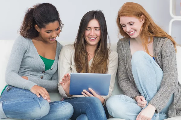 Amigos femeninos usando tableta digital juntos en el sofá —  Fotos de Stock