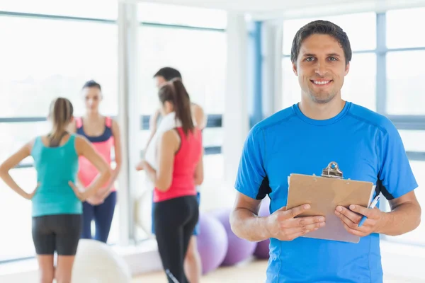Trainer mit Fitnesskurs im Hintergrund im Fitnessstudio — Stockfoto