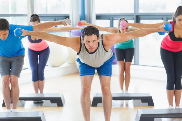 Instructor con clase de fitness realizando ejercicios aeróbicos paso a paso con pesas —  Fotos de Stock
