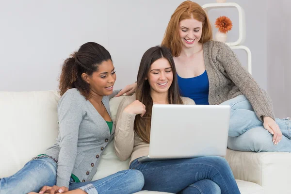 Vrolijke vrouwelijke vrienden met behulp van laptop samen op sofa — Stockfoto