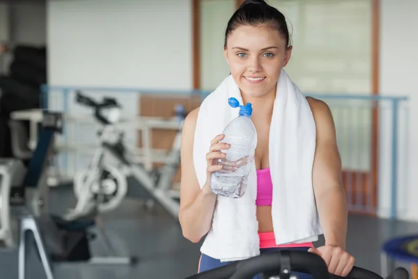 Mujer cansada bebiendo agua mientras hace ejercicio en la clase de spinning —  Fotos de Stock