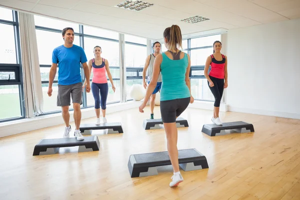 Instructor con clase de fitness realizando ejercicios aeróbicos paso a paso —  Fotos de Stock