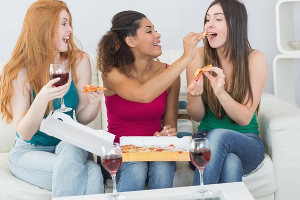 Amigas felizes comendo pizza com vinho em casa — Fotografia de Stock