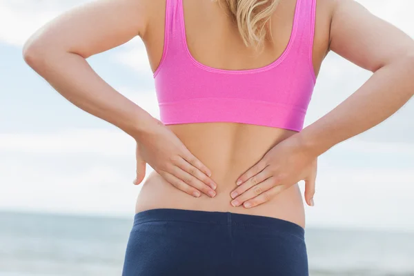 Mid section of toned woman from back pain on beach Stock Image