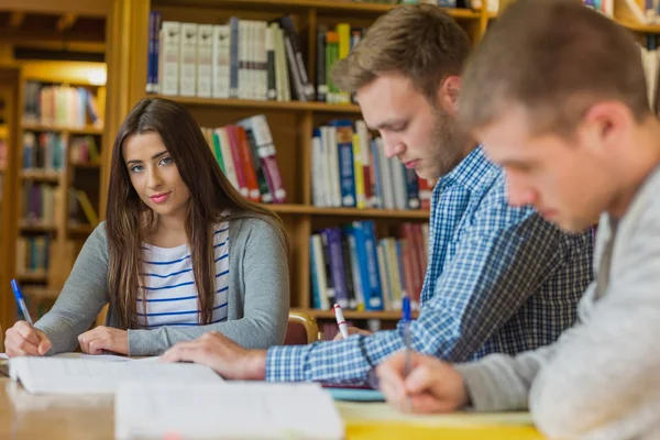 Students writing notes at library desk Stock Photo