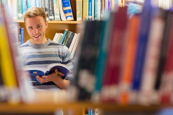 Mannelijke student boek in de bibliotheek te selecteren — Stockfoto