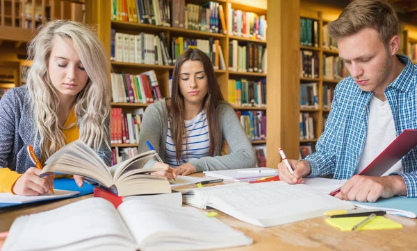 Studenten schreiben Notizen am Büchertisch — Stockfoto