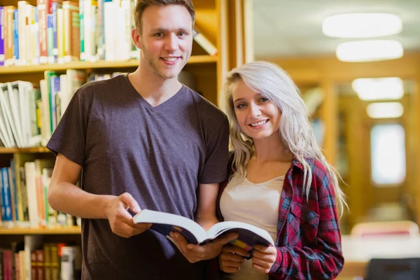 Estudantes em pé junto à estante da biblioteca — Fotografia de Stock