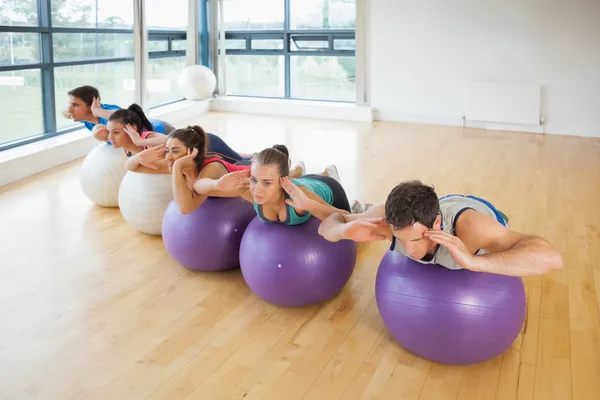 Fitnessklasse, die hintereinander auf Fitnessbällen trainiert — Stockfoto