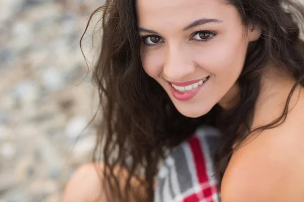 Mujer joven sonriente cubierta con manta en la playa — Foto de Stock