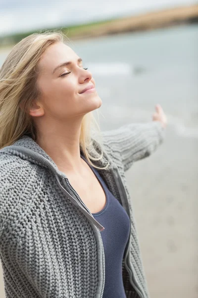 Sidovy av en kvinna som sträcker sina armar på stranden — Stockfoto