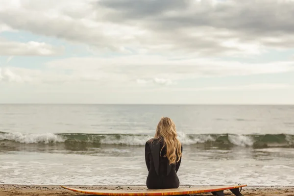 Rückansicht der Blondine im Neoprenanzug mit Surfbrett am Strand — Stockfoto